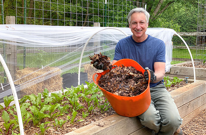 Gardener spreading mulch on garden bed in autumn - Best Mulch for a Vegetable Garden | Three Top Choices | joegardener®