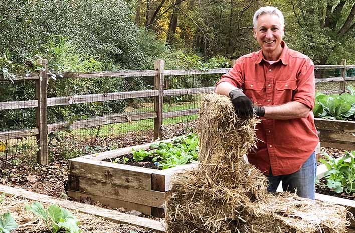 Gardener spreading mulch on garden bed in autumn - Why Mulch Matters | Everything You Need to Know | joe gardener®