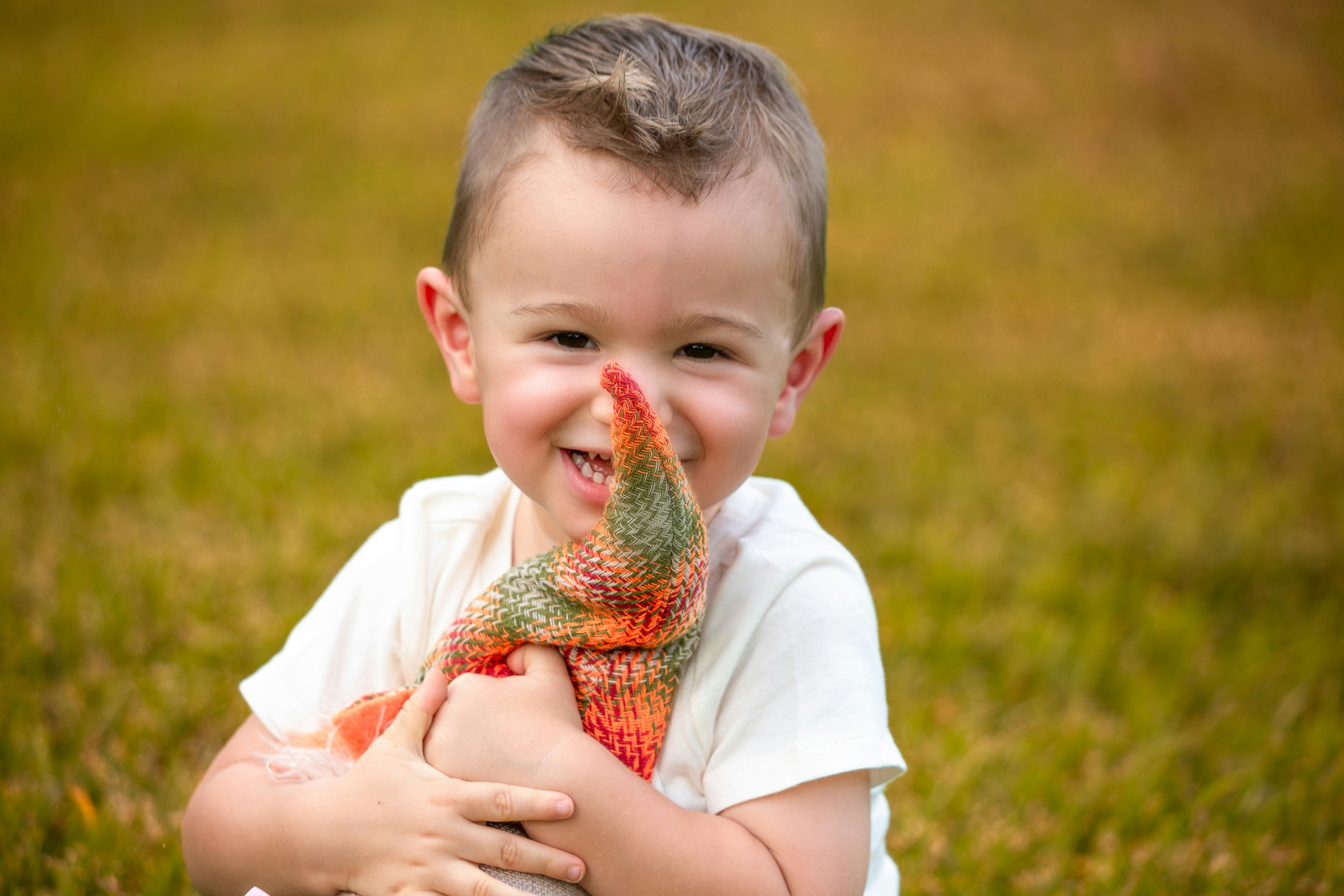 Child holding bearded dragon - A smiling young boy holding a colorful stuffed toy.