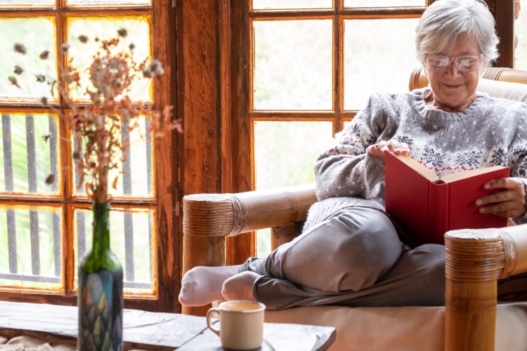 Focused woman reading in cozy chair with tea - 6 Ways To Stay Physically and Mentally Active During Winter as a ...