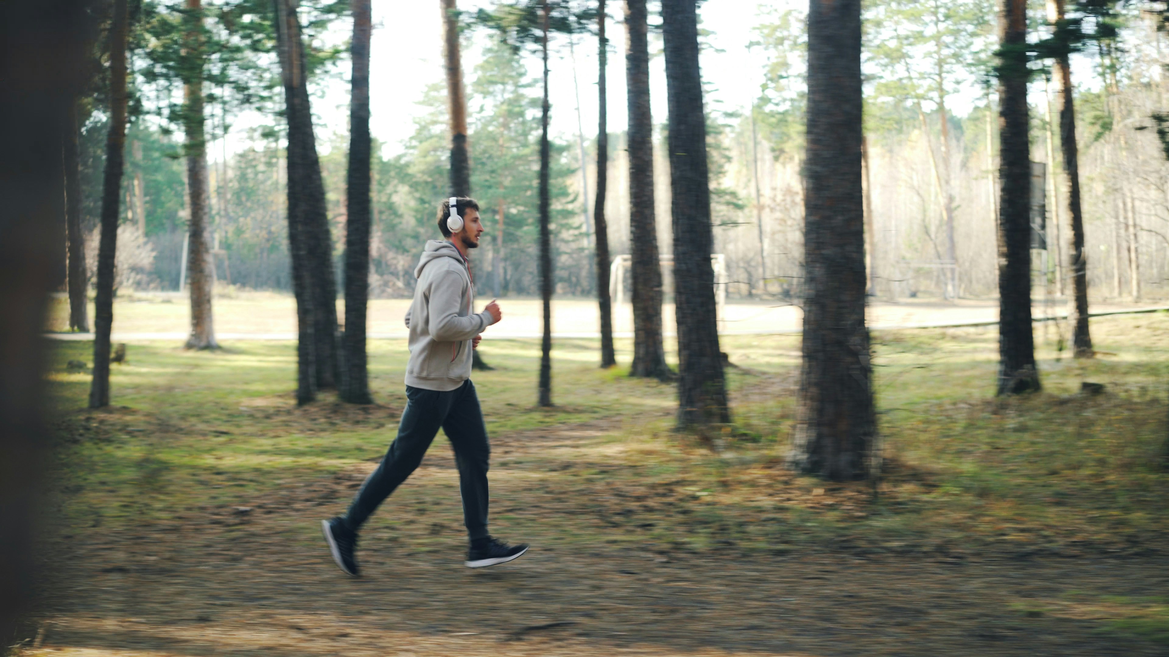 man running outdoors with biometric data overlay - Man running with headphones in a forest