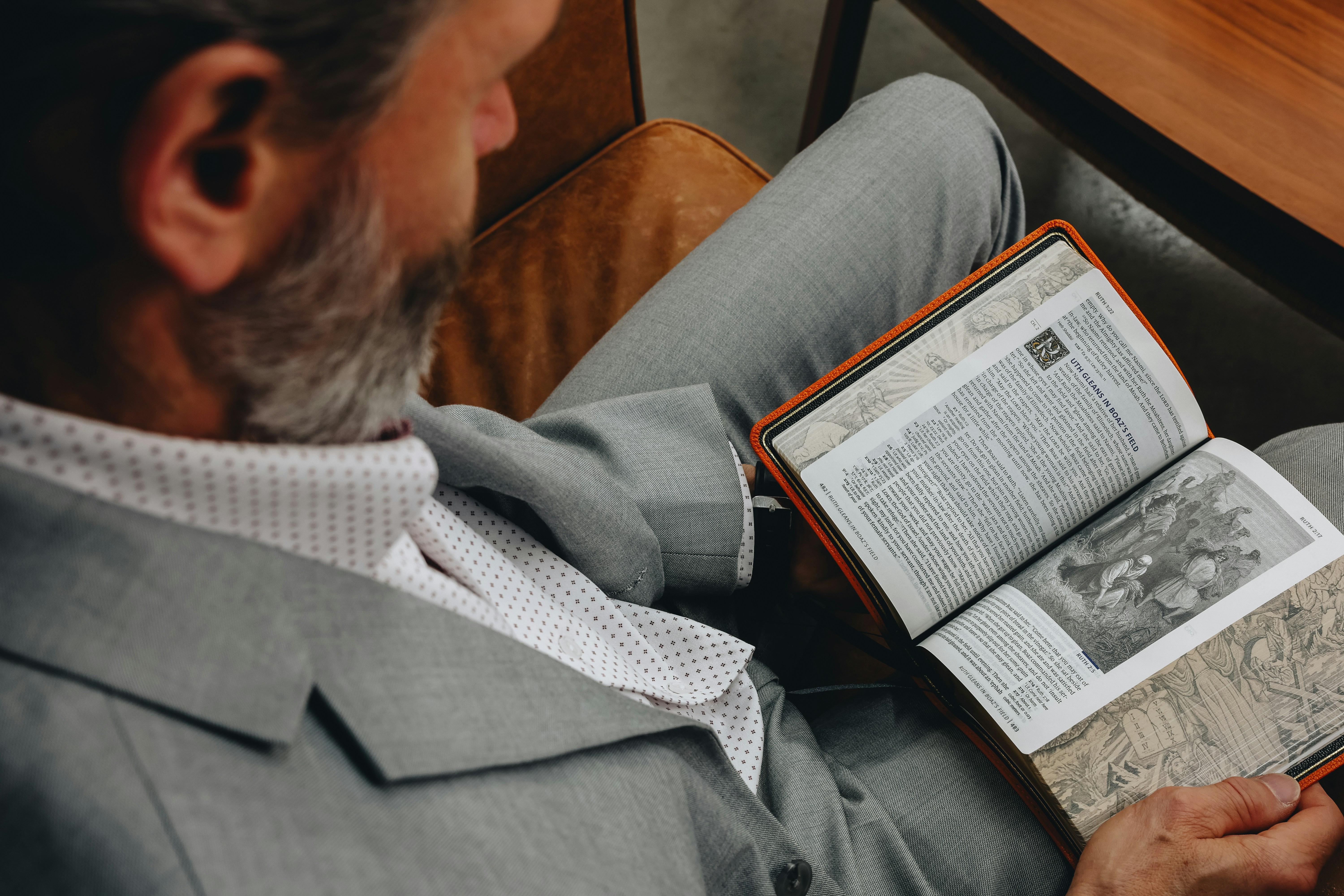 Person reading digital fashion magazine on tablet - A man sitting in a chair reading a book